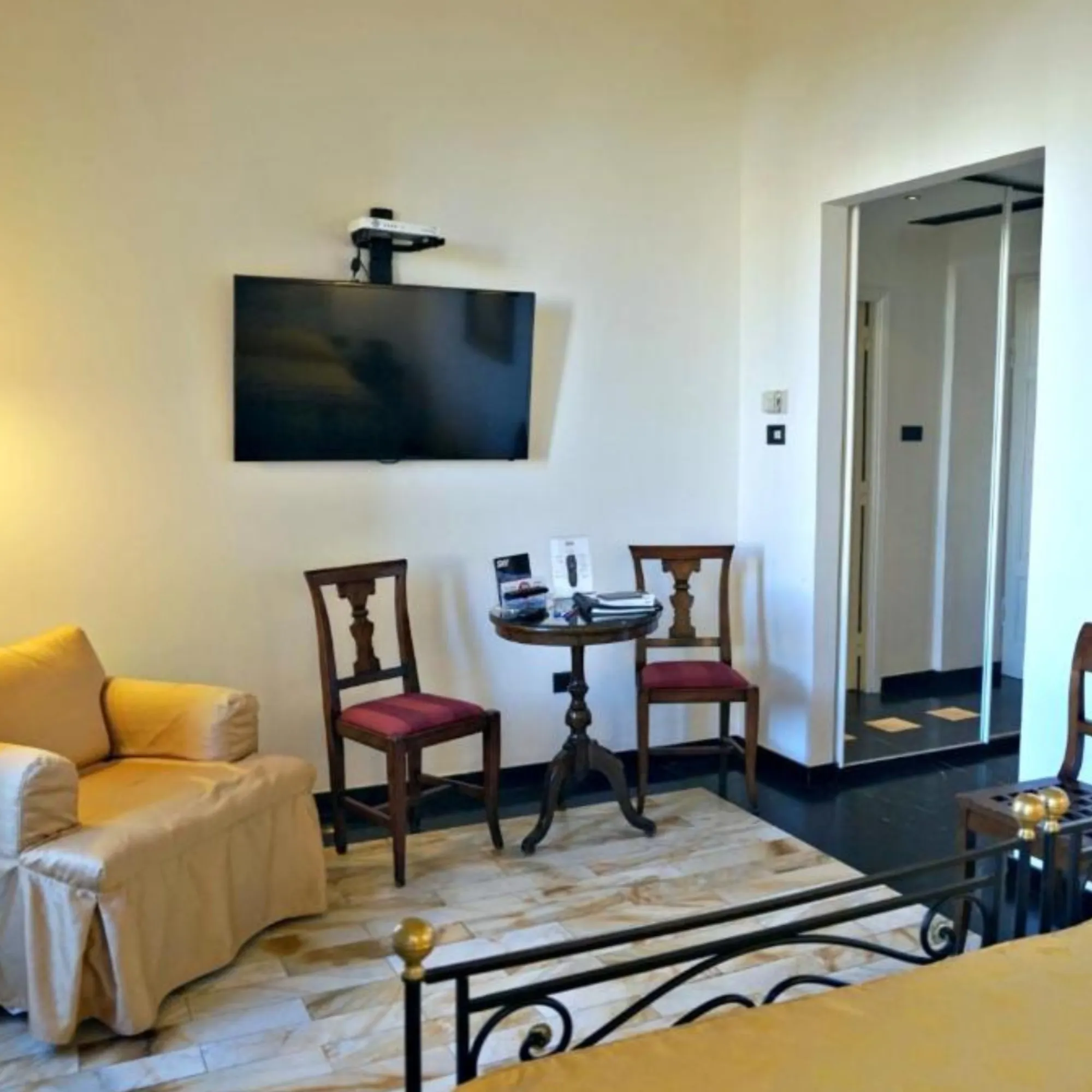 Area living della Camera Tripla a Villa Las Tronas Hotel & Spa, con poltrona ocra, sedie d'epoca, tavolino in legno e TV a schermo piatto.