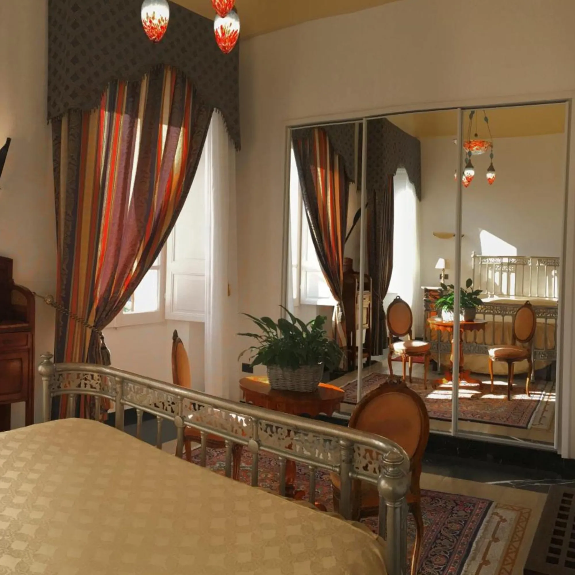 Suite di Villa Las Tronas Hotel & Spa con ampio specchio a parete, letto classico, arredi d'epoca e riflessi di luce naturale.